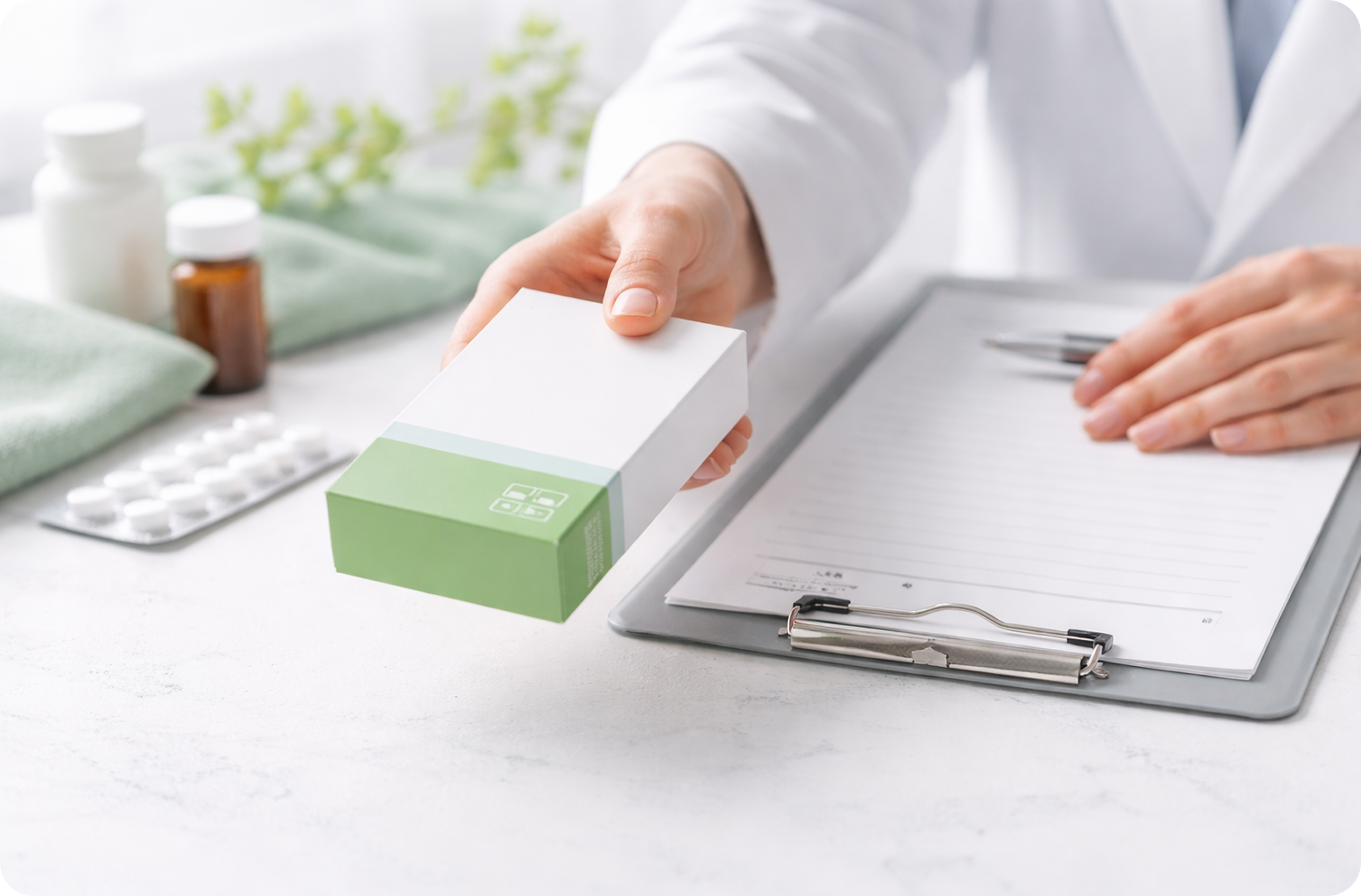 Doctor handing over a medicine box beside a clipboard and prescription pad